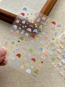 Dettaglio degli adesivi colorati con maglioni invernali per nail art a tema autunnale