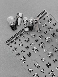 Macro detail of silver bow and heart nail stickers with elegant 3D metallic texture