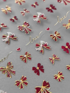 Macro shot of 3D embossed red bow nail stickers with gold edges and love letters