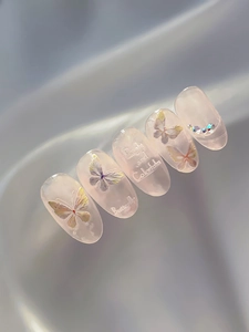 Macro shot of oval butterfly nail stickers with rhinestones on silk fabric background