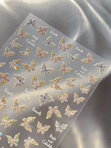 Macro shot of 3D iridescent butterfly nail stickers with aurora finish and relief texture