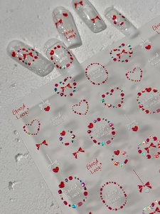 Détail de stickers 3D pour ongles avec nœuds rouges, cœurs et bijoux sur faux ongles