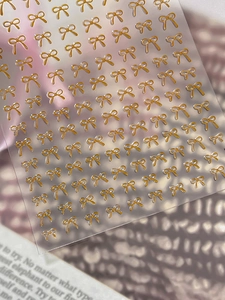 Close-up of 3D gold embossed bow nail art stickers with elegant textured relief detail