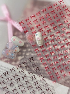 Detail view of 3D embossed red and black bow nail stickers with refined relief texture