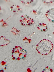 Vue macro de stickers d'ongles 3D avec cœurs rouges, nœuds et strass brillants