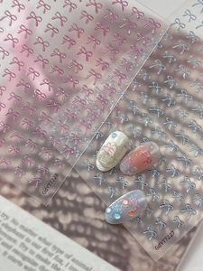 Macro view of 3D embossed bow nail art stickers in pink and blue translucent designs