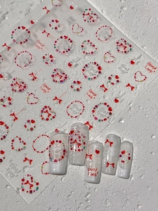 Détail des stickers ongles avec cœurs rouges, nœuds et nail art avec gemmes 3D brillantes