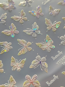 Macro shot of 3D holographic shell butterfly nail art stickers with embossed texture