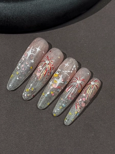 Dettaglio di unghie finte stiletto lunghe con fuochi d'artificio rossi e glitter