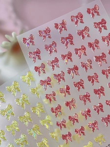 Detailed holographic 3D bow nail stickers in pink and yellow with embossed texture
