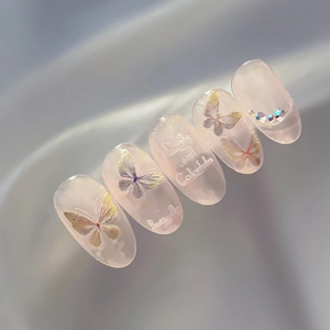Handmade almond butterfly nail stickers in translucent nude pink with relief text and rhinestones