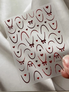 Détail macro de stickers à ongles rouges avec cœurs et nœuds sur les doigts