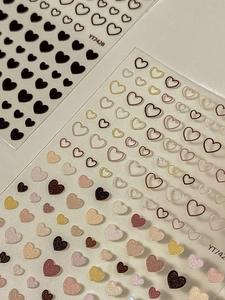 Gros plan d'autocollants pour ongles avec cœurs minimalistes et finitions à paillettes