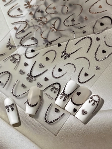 Détail d'autocollants nail art à nœuds en relief et texture tweed sur ongles blancs