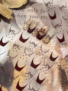 Autocollants pour ongles bordeaux avec nœuds et pois sur fond de feuilles d'automne