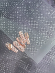 Close-up of pink coffin press-on nails with white fish scale texture and pearl accents