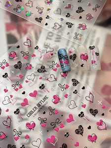Dettaglio di adesivi per unghie 3D con cuori rosa e fiocchi su foglio trasparente e tips