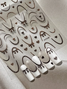 Détails d'autocollants ongles léopard avec nœuds et cœurs sur manucure blanche