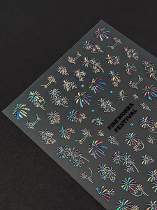 Macro shot of holographic 3D fireworks nail art stickers on a textured black background