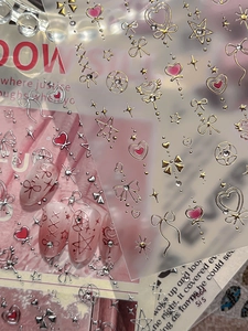 Close-up of 3D embossed nail stickers featuring gold heart and bowknot patterns