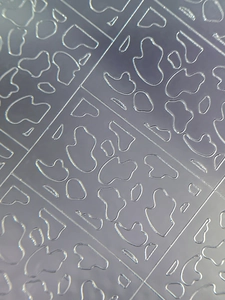 Macro detail of silver embossed checkered patterns on translucent nail art stickers