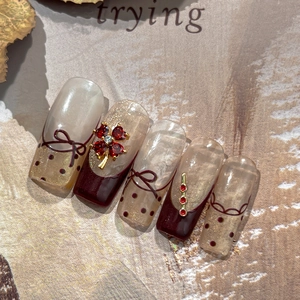 Faux ongles bordeaux et nus élégants avec nœuds 3D et breloques trèfle serties