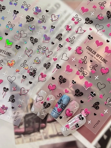 Dettaglio di adesivi olografici per unghie con motivi a cuore e fiocco in stile Y2K