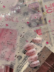 3D metallic silver heart and bow nail art stickers on pink cat-eye press-on nails