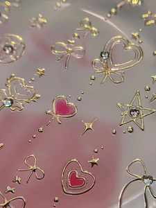 Detail of 3D nail stickers with golden bows, crystal hearts, and stars design