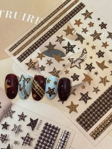 Detailed view of houndstooth and star nail stickers with golden autumn style accents