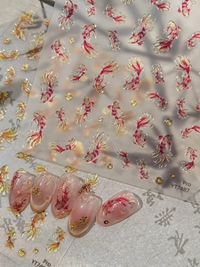 Close-up of Koi fish nail stickers with gold foil relief and red accents on pink nails