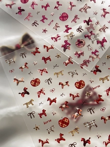 Macro detail of plaid horse nail stickers with red apple and bow tie patterns