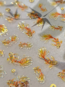 Macro shot of 3D koi fish nail art stickers with golden glitter and water drop effect
