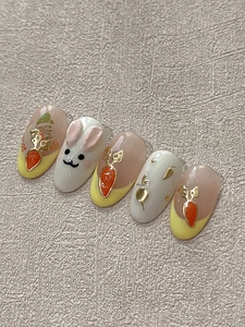 Dettaglio di adesivi nail art 3D con coniglietto e carota, accenti dorati e punte french