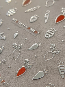 Dettaglio macro di adesivi 3D per unghie con carote in argento e arancione