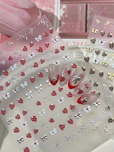 Detail of sweet strawberry and bow nail art decals on French manicure tips