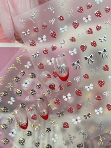 Detail of strawberry and 3D bow nail art stickers showing high-quality texture and design