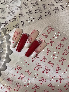 Detail shot of 3D bow nail stickers with pearls and dotted patterns on false nails