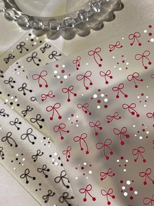 Detailed view of red, black, and white 3D bow and dot nail art stickers for DIY manicure