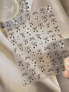 Close-up of minimalist embossed bow and polka dot nail art stickers on a sheet