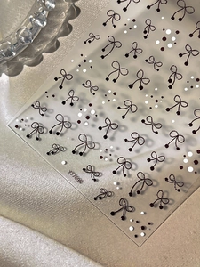 Macro detail of 5D embossed nail stickers with black bows and polka dot patterns