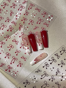 Close-up of red and black bow-knot nail art stickers showing relief pattern and 3D application