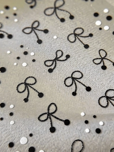 Macro detail of embossed 3D black bow and polka dot nail stickers with textured surface