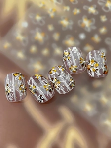 Gros plan sur des faux ongles violets avec motifs floraux dorés et détails de perles