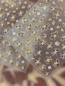 Détail macro d'autocollants 3D dorés pour ongles avec des motifs floraux métalliques