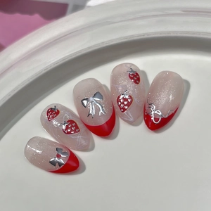 Custom strawberry press-on nails with silver bows and red French tips on glitter base