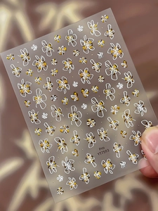 Gros plan d'autocollants pour ongles fleurs blanches avec touches dorées et code YT7593