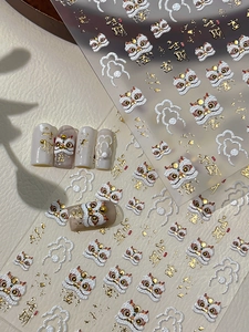Vista macro di adesivi 3D per unghie con motivi di danza del leone e dettagli dorati
