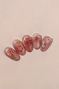 Detail of pink cat-eye press-on nails with holographic stars and hand-painted fireworks