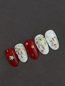Close-up of festive red and white nail art tips with 3D gold bells and fireworks design